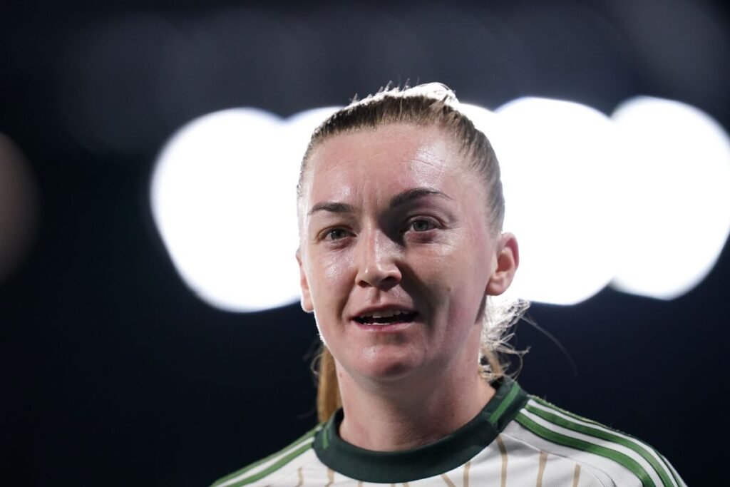 Female athlete speaking or addressing a crowd wearing a green and white striped sports jersey under stadium lights close up portrait