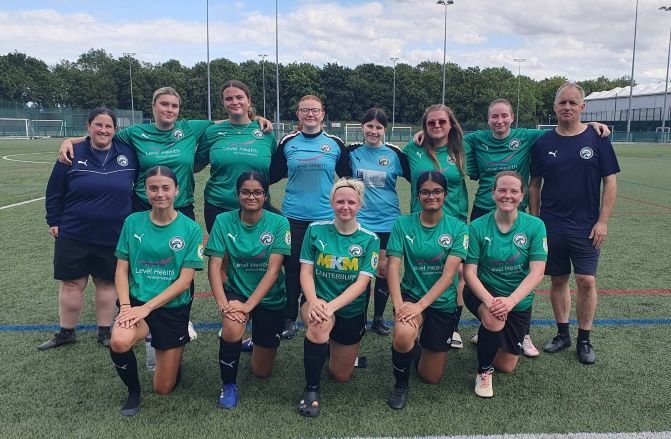 CanterburyEagles womensfootballmagazinecom Group photo of a womens soccer team in green jerseys kneeling in front row and standing in back on a turf field with two coaches at the ends