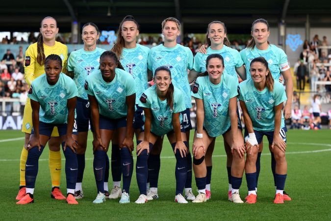 SPP1454263 womensfootballmagazinecom Womens soccer team posing for a group photo on the field in turquoise jerseys and navy shorts